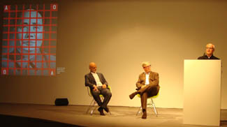 Dr. Uli Sigg, Dr. Lars Nittve and Michael Lynch (from left) discuss the donation of the majority of the Sigg collection of Chinese contemporary art worth US $ 163 million to a single museum at a media conference at Art Basel. Painting projected: Wang Guangyi, <i>Mao Zedong: Red Grid No. 2 </i>1988